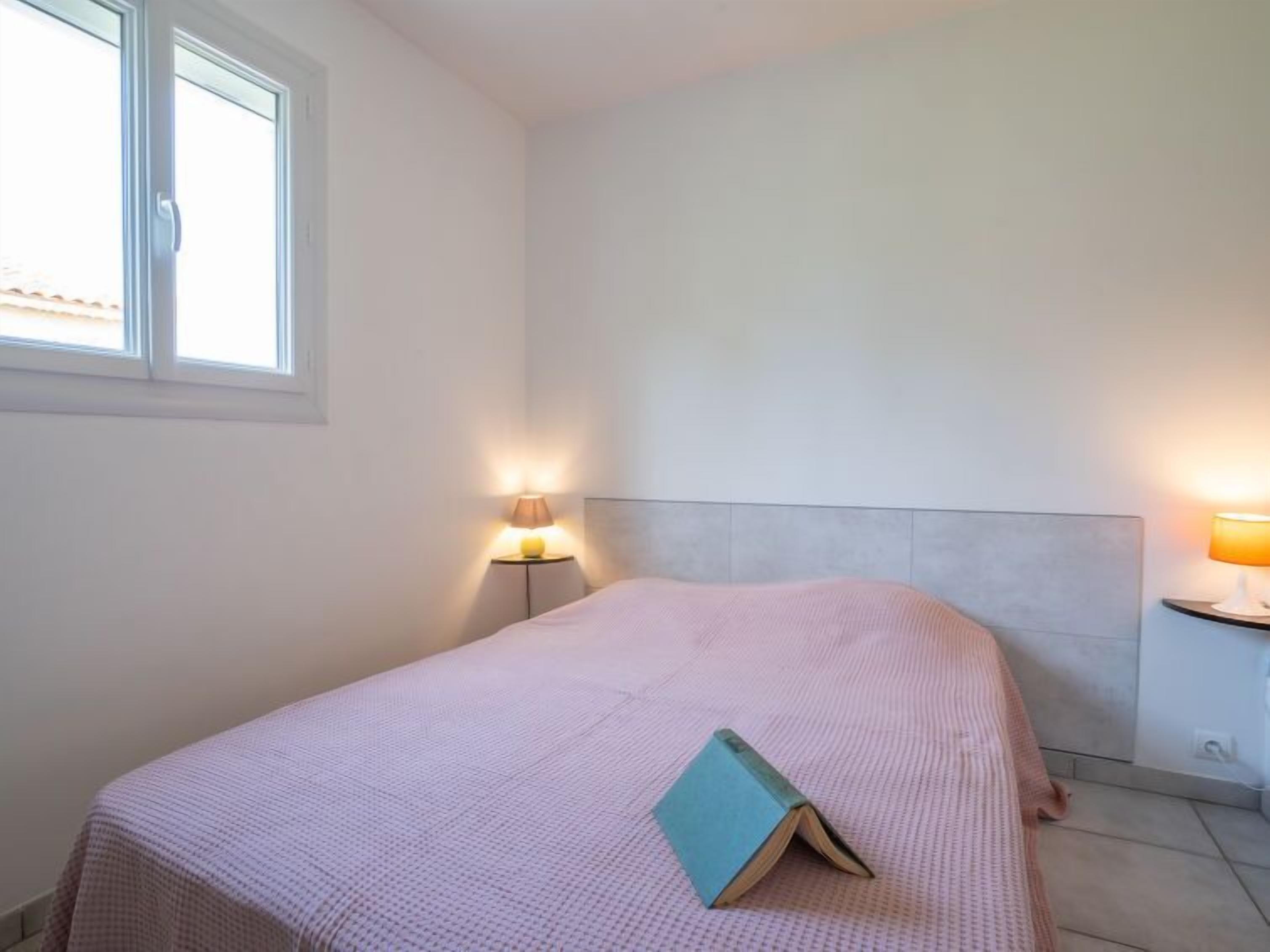 Un dormitorio con una cama, dos lámparas de noche y una ventana.