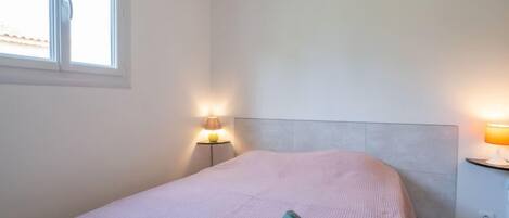 Un dormitorio con una cama, dos lámparas de noche y una ventana.