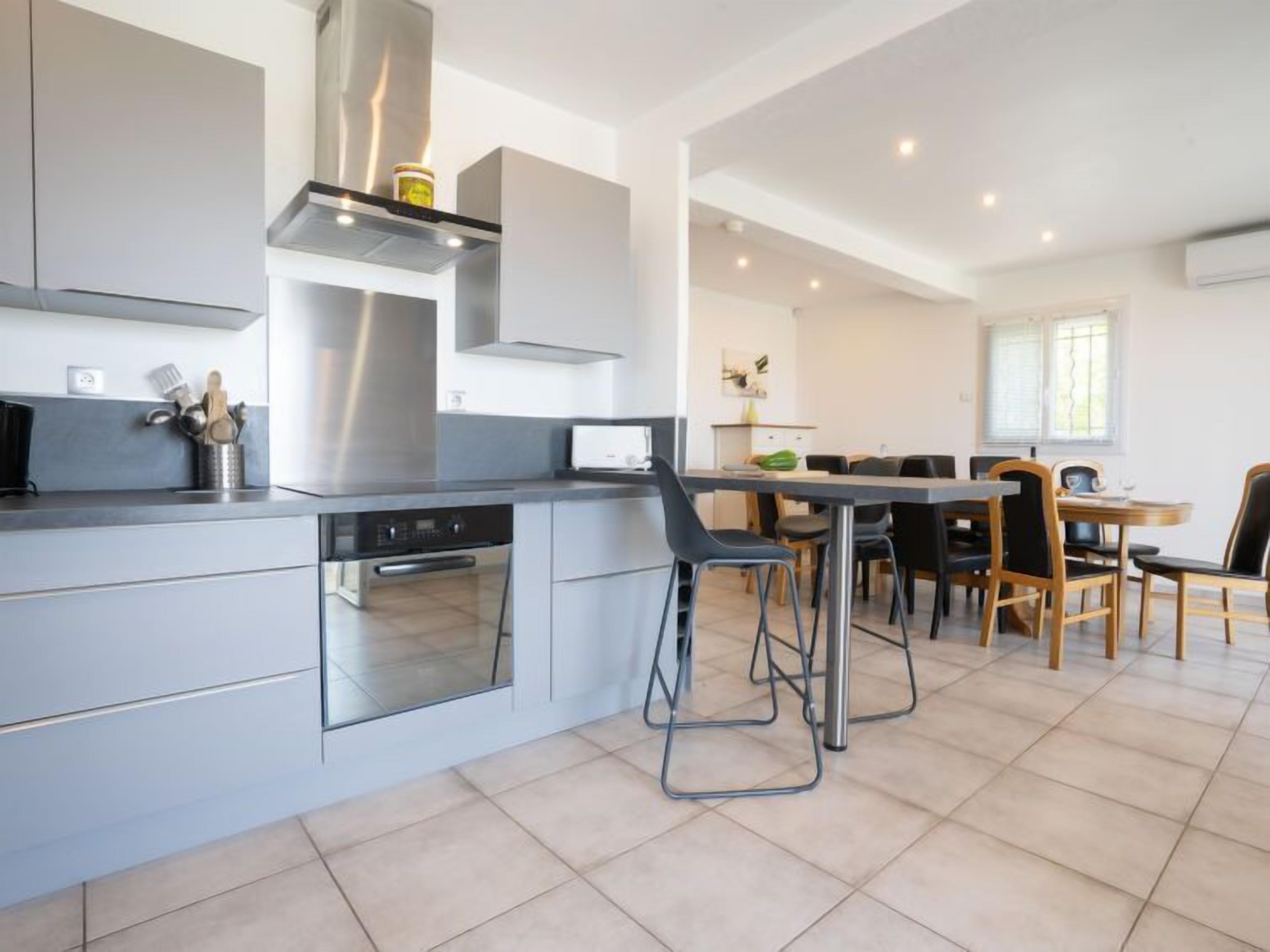 A modern kitchen with a central island, built-in oven, and stainless steel range hood.