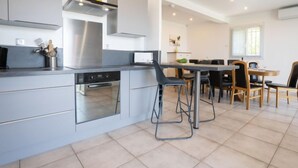 Una cocina moderna con una isla central, horno empotrado y campana de acero inoxidable.