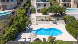 Zona residencial con piscina rodeada de sillas de descanso y sombrillas, lo que sugiere un espacio al aire libre privado.