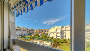 Un balcón con vistas a una zona residencial, con edificios de apartamentos y un jardín cercado.