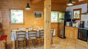 Puinen mökki, jonka sisätiloissa on ruokailutila, keittiö ja suuri puupalkkirakenne.