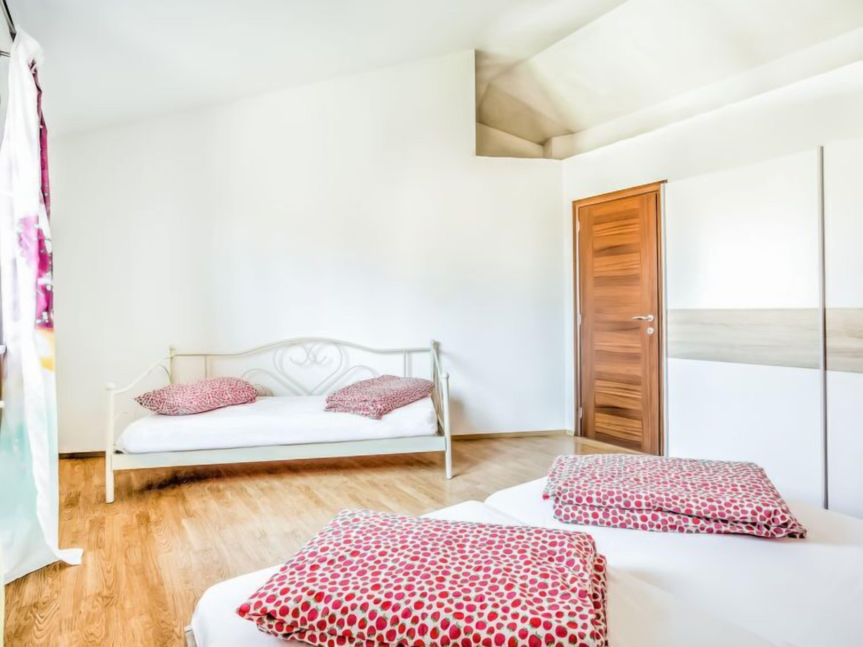 A bedroom with a white metal bed frame, two pillows, a wooden door, and a white wall.