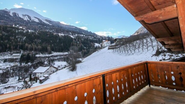 Ein Holzbalkon mit Blick auf eine verschneite Berglandschaft.