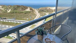 A balcony with a glass table, two wine glasses, and a potted plant.
