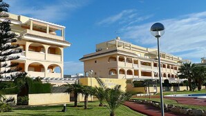 Un hôtel doté de nombreux balcons, d’une piscine et d’une pelouse bien entretenue.