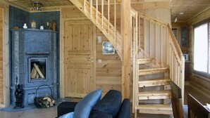 Un interior de madera con una escalera, una chimenea y un sofá.