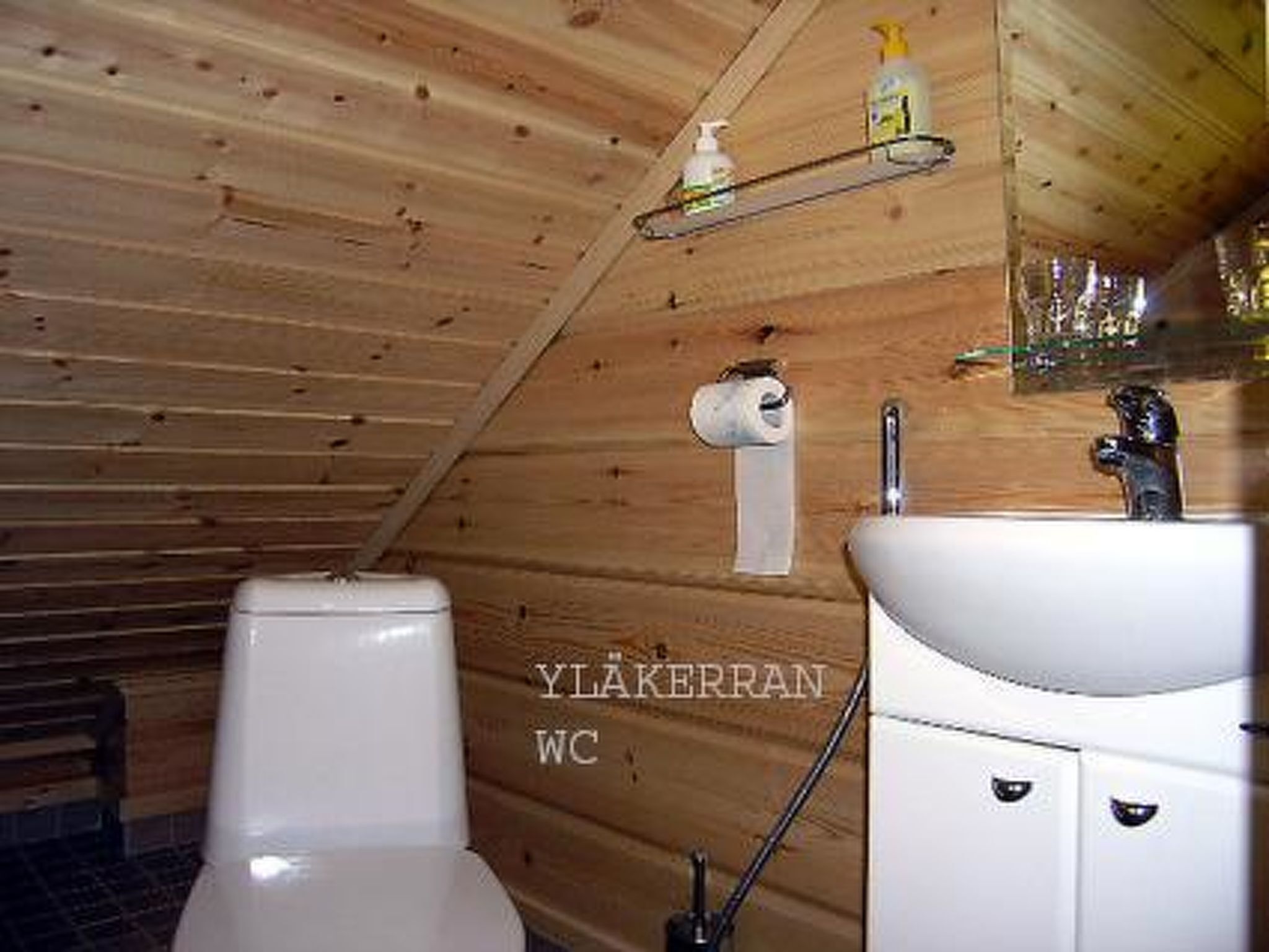 Un baño con paneles de madera, un inodoro, un lavabo y una repisa con artículos de tocador.