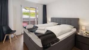 A modern hotel room with a large bed, a desk, and a view of the outdoors. - Allod Park Haus C 106 by Interhome (Davos)