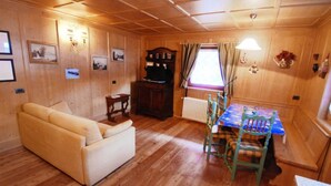 Une pièce chaleureuse avec des murs et un plancher en bois, un canapé, une table avec des chaises et un radiateur.