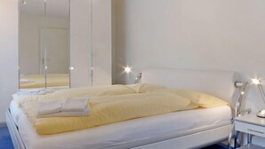 Un dormitorio moderno con una cama grande, una mesita de noche, un espejo y un escritorio con silla.