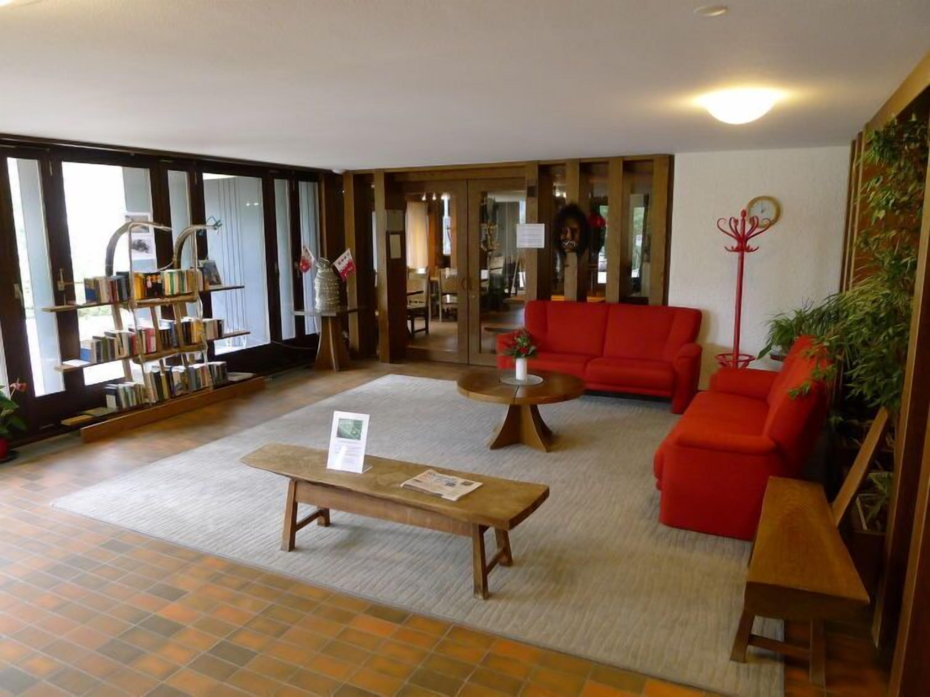 Eine großzügige Lobby mit einem roten Sofa, einem Holztisch und einem Bücherregal.