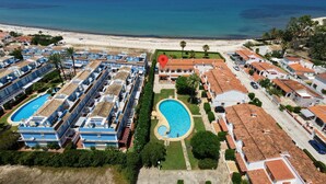 Een resort met meerdere gebouwen, een zwembad in het midden en uitzicht op het strand.