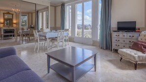 A spacious living room with a dining area, a television, and a balcony with a view. - Marie Antoinette by Interhome (Cabourg)