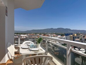 Ein Balkon mit Esstisch, mit Blick auf Stadt und Berge.