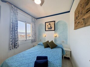 Ein Schlafzimmer mit einem Bett, Vorhängen, einem Wandbild und einem Fenster mit Blick.