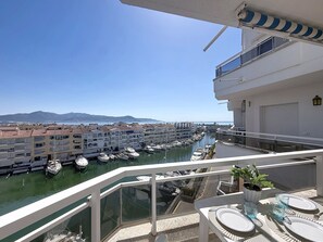 A balcony with a view of a marina, dining table set, and a potted plant. - Club Nautic by Interhome (Empuriabrava)