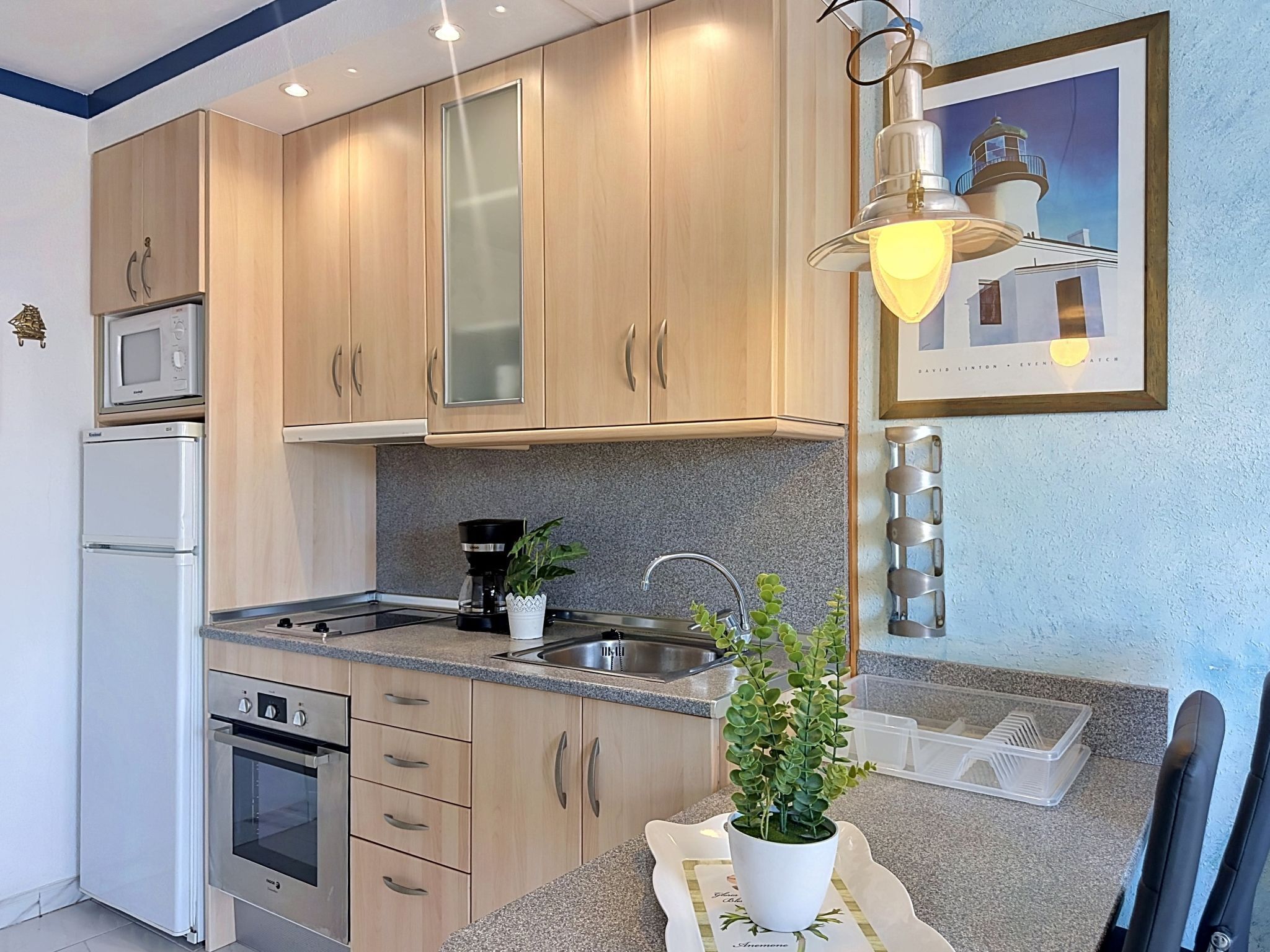 A modern kitchen with wooden cabinets, a built-in microwave, a coffee maker, and a sink.
