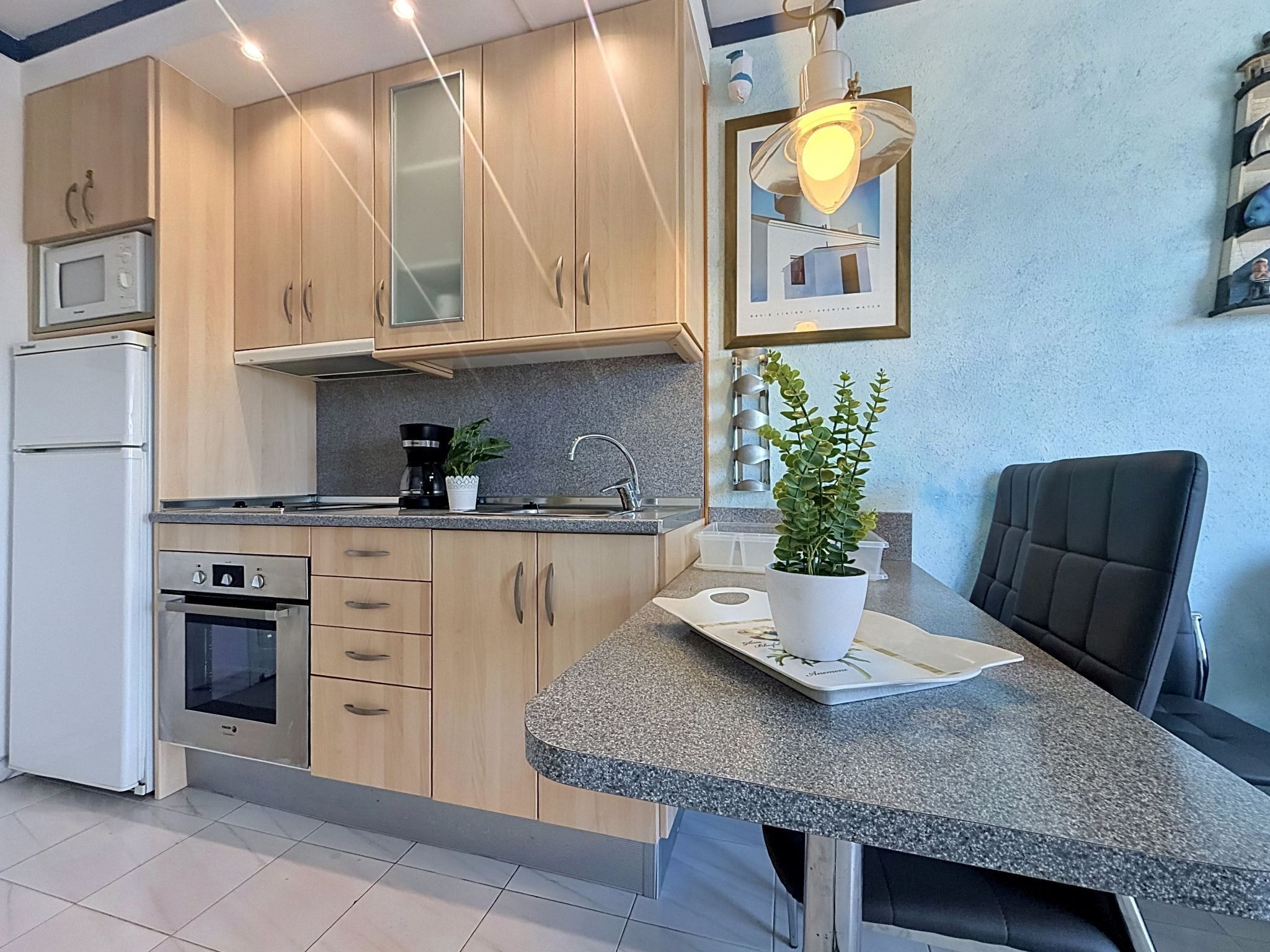 A modern kitchen with wooden cabinets, a built-in oven, a coffee maker, and a potted plant.