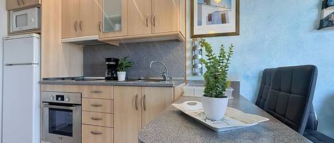 A modern kitchen with wooden cabinets, a built-in oven, a coffee maker, and a potted plant.
