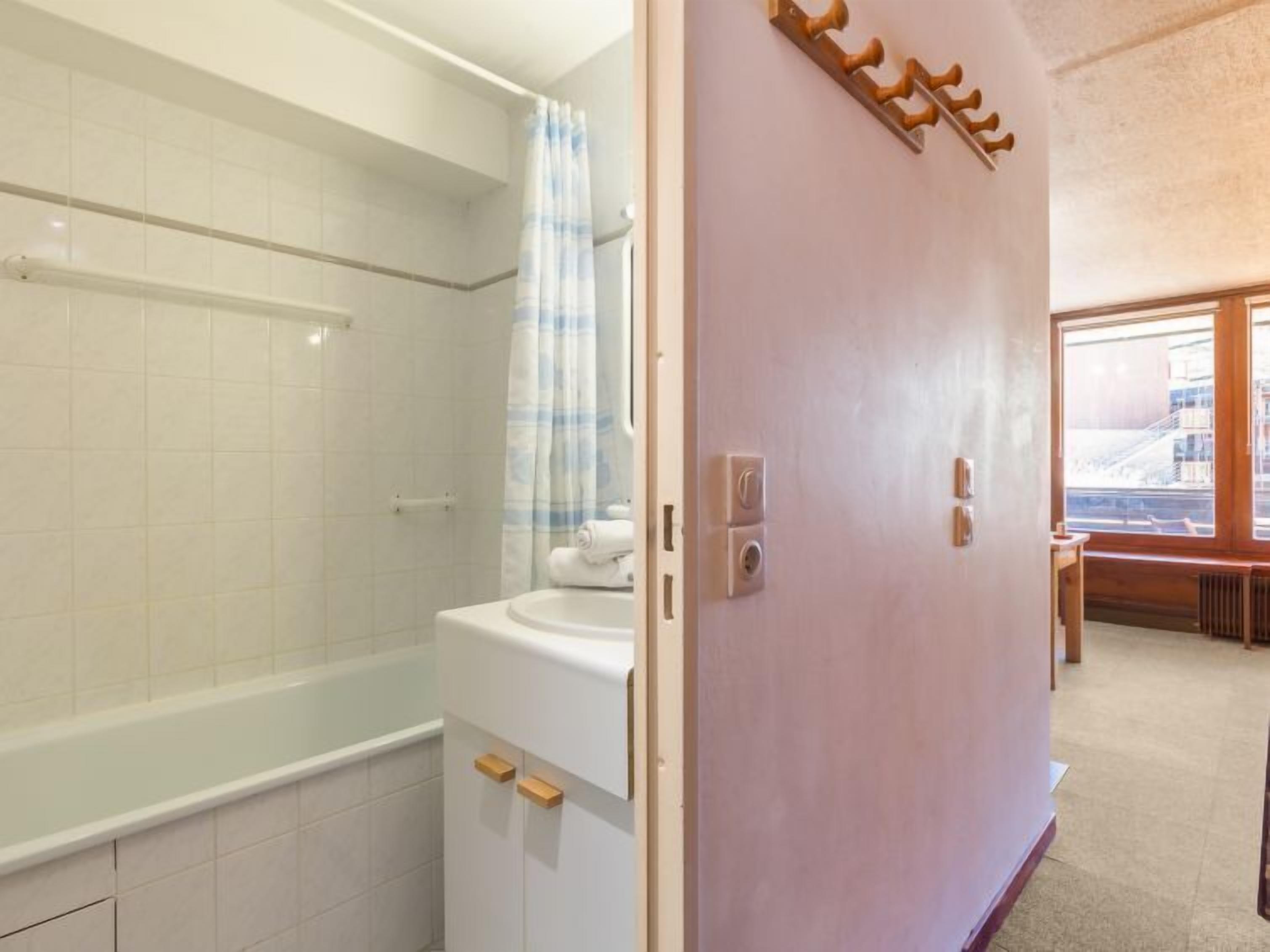A bathroom with a bathtub, a shower, and a toilet. There is a towel rack on the wall and a window providing natural light.