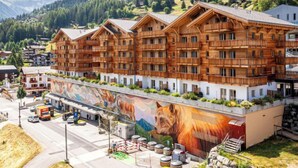 Un edificio de madera de varios pisos con balcones, con montañas al fondo.