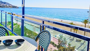 Un balcon avec vue sur la mer et la plage, comprenant une table avec deux bols et une chaise.