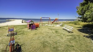 Une aire de jeux sur la plage, avec des balançoires et un petit abri.