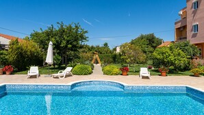 Une piscine avec des chaises longues et des plantes en pot.