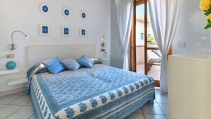 Un dormitorio con cama, mesita de noche, lámpara y ventana con cortinas.