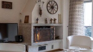 A living room with a fireplace, white furniture, and a television.