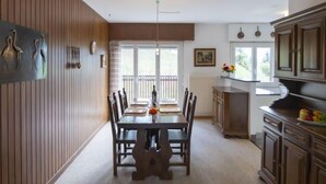 A dining area with a wooden table and chairs, a pendant light, and a view of the outdoors through a sliding glass door.