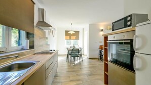 A modern kitchen with a central island, built-in oven, microwave, and stainless steel appliances. - Apartment Marija by Interhome (Krk/Omišalj)