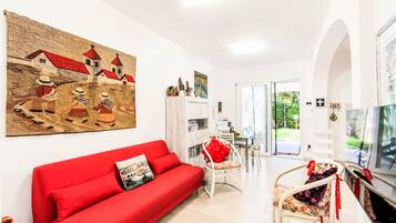 A modern living room with a red sofa, a TV, and a large painting on the wall.