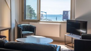 Un soggiorno moderno con un'ampia finestra a bovinda, una televisione a schermo piatto e un'area salotto confortevole.