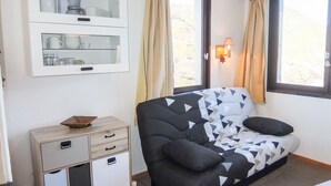 Une chambre à coucher avec un lit, une commode, un miroir et une fenêtre avec des rideaux.