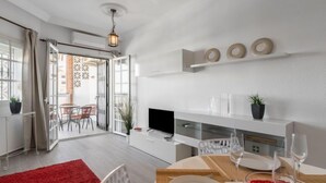 Ein modernes Wohnzimmer mit Essbereich, Fernseher und einem roten Teppich.