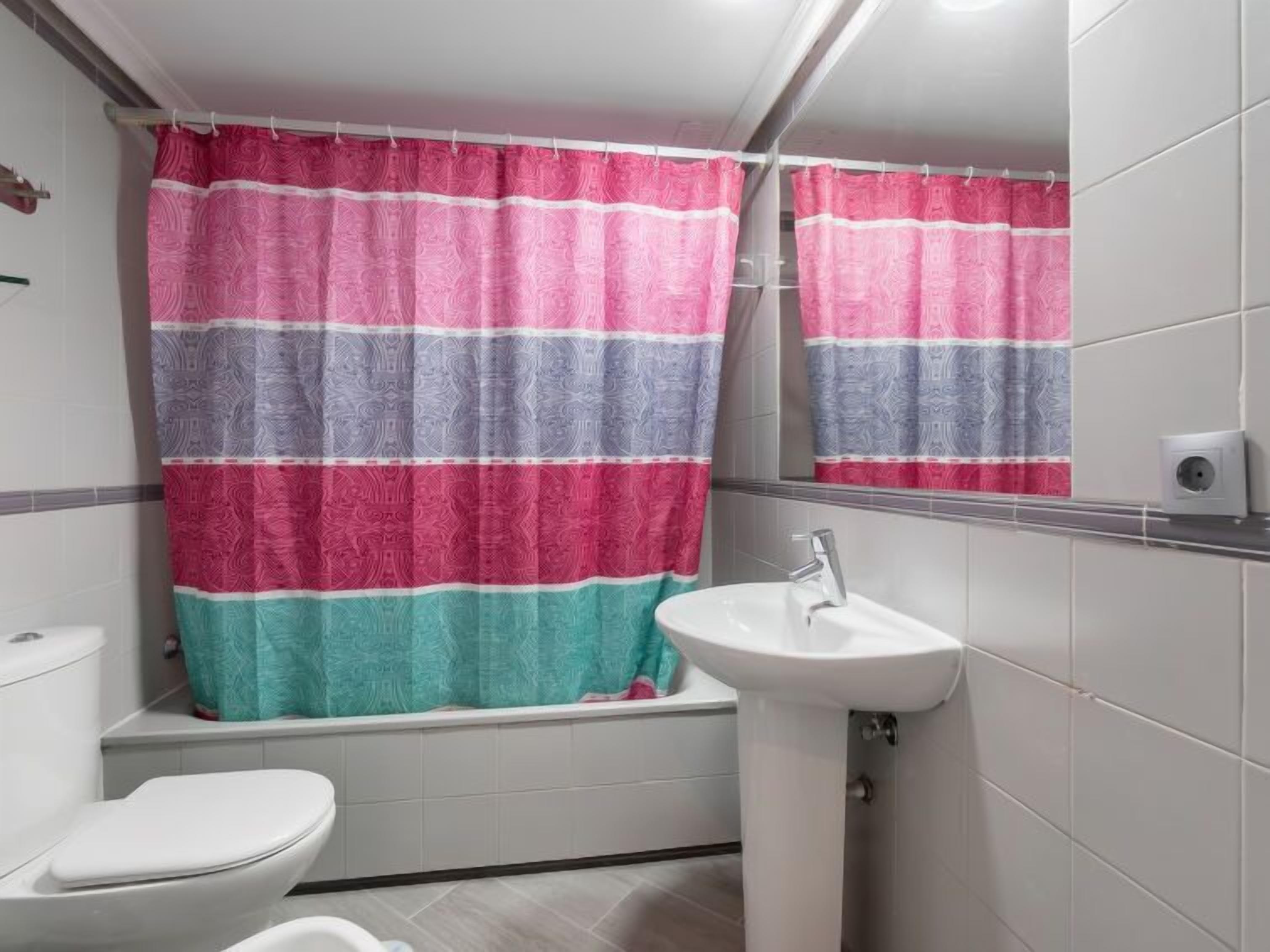 A bathroom with a striped shower curtain, a white sink, and a toilet.