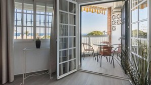 Ein Zimmer mit einer Schiebeglasdoor zum Außenbereich, der einen Tisch, Stühle, einen Blumentopf und Meerblick bietet.