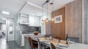 A modern kitchen with white cabinets, a wooden accent wall, and pendant lighting. - Le Pramecou (Val Claret) by Interhome (Tignes)