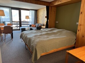 Une chambre avec un grand lit, un canapé, une table à manger et une vue sur l’extérieur.