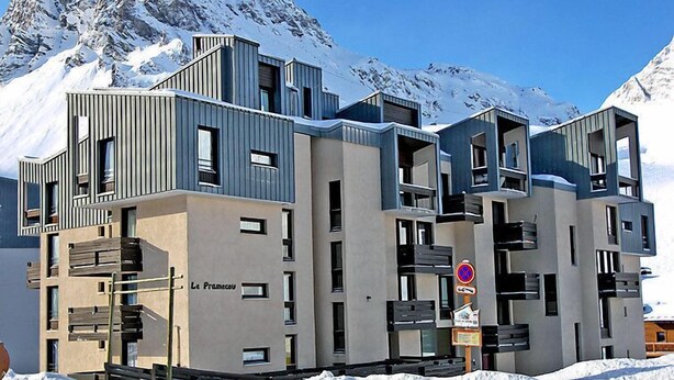 Ein modernes, mehrstöckiges Gebäude mit Balkonen und Fenstern in einer verschneiten Berglandschaft.