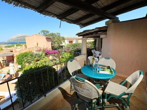 Eine Terrasse mit Tisch und Stühlen, einem Geländer und Blick auf das Meer und Gebäude.