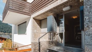 Un bâtiment moderne avec une façade en pierre, un escalier en bois et une rampe métallique.