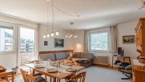 Un salon moderne comprenant un coin repas, de grandes fenêtres, un canapé et un téléviseur.
