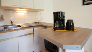 A compact kitchen with white cabinets, a stainless steel sink, and a coffee maker on the counter. - Vostok Zodiaque by Interhome (Le Corbier)