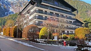 Een hotel met meerdere verdiepingen en balkons, omringd door herfstbladeren en bergen.