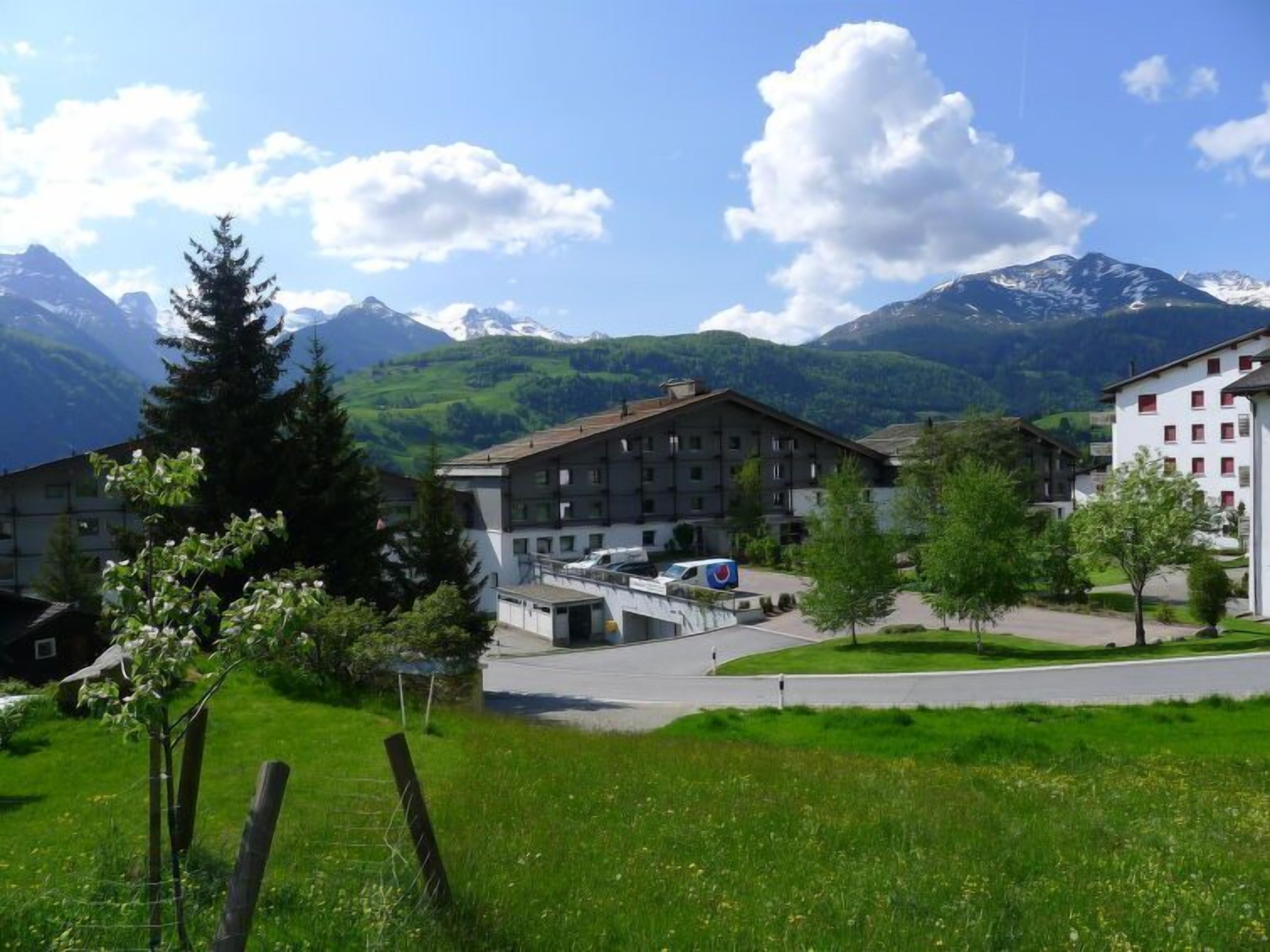 A hotel with a modern design, featuring a central courtyard and a view of mountains.