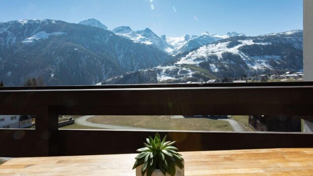 Ein Balkon mit Blick auf schneebedeckte Berge und einen klaren Himmel.